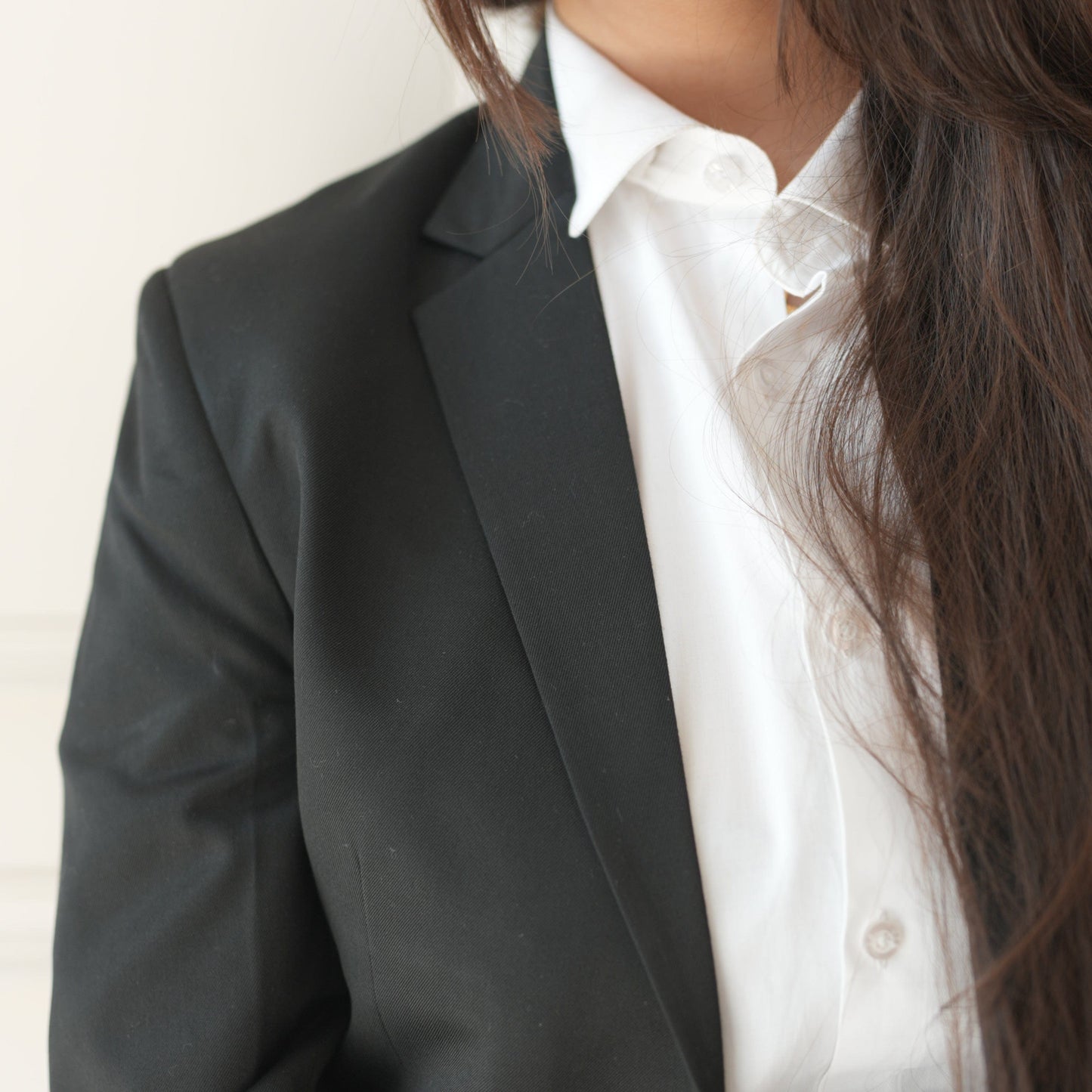 Person wearing a black coat over a white shirt with a neutral background
