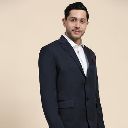 Man wearing a navy blazer with a red pocket square on a beige background
