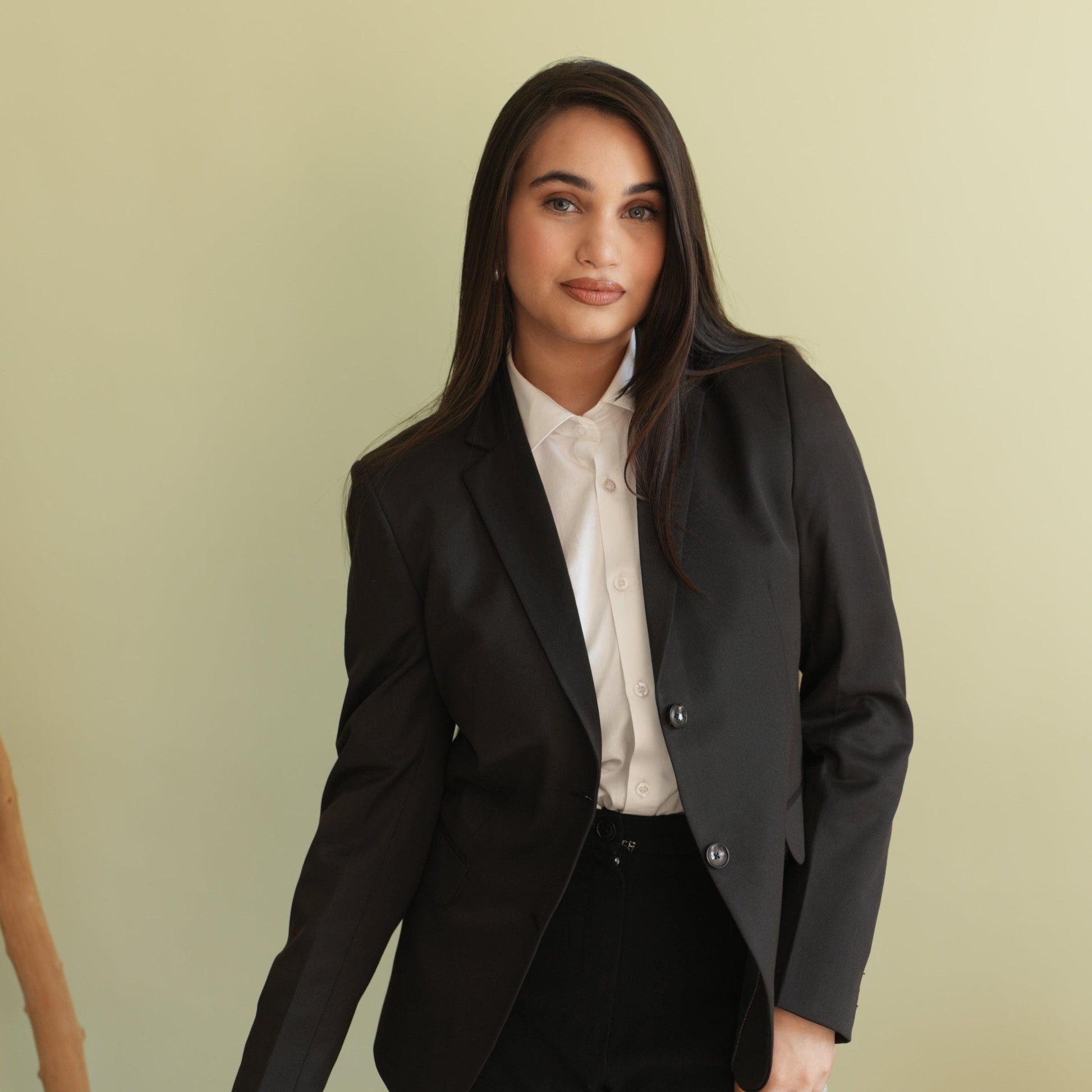 Woman wearing a black blazer over a white shirt against 
