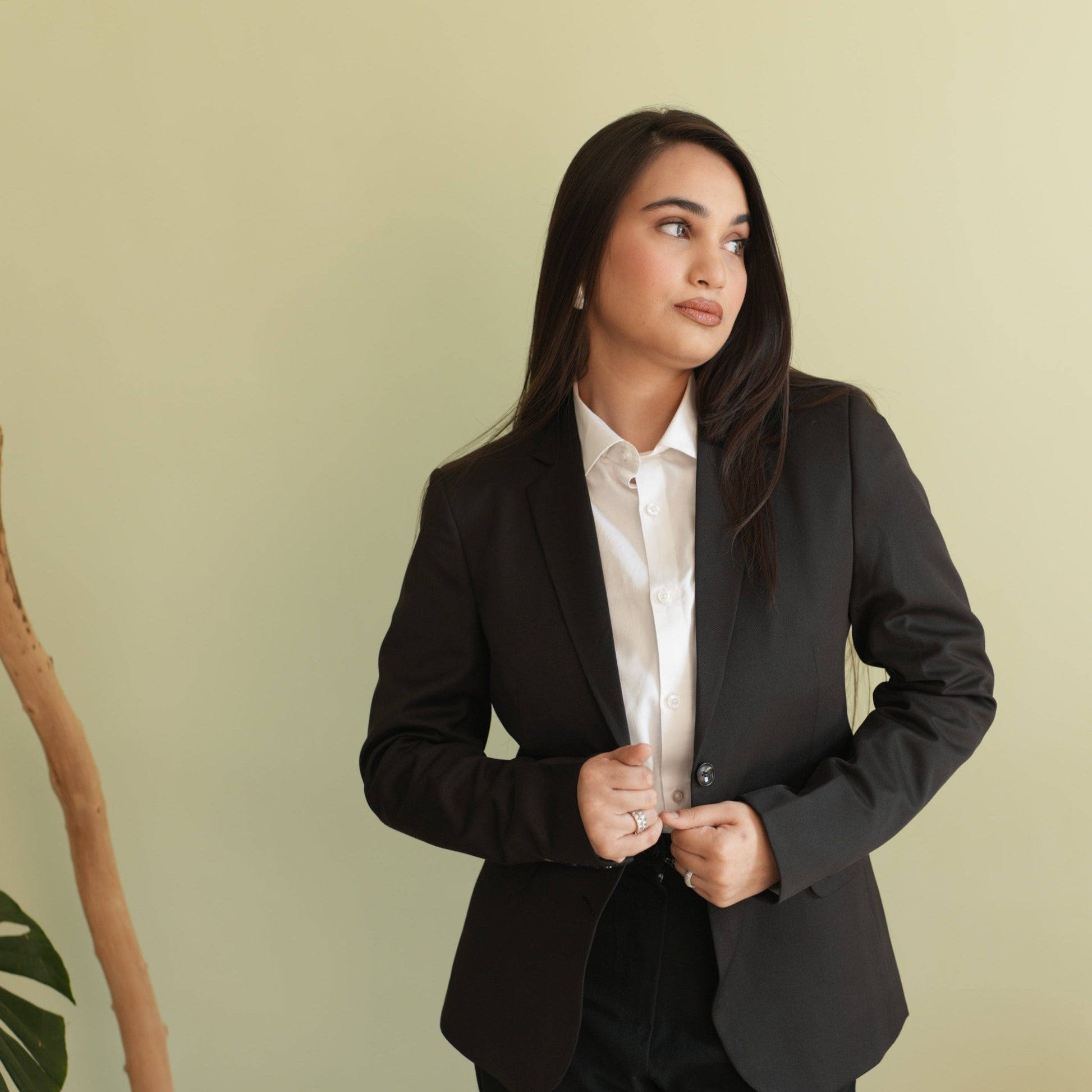 Woman wearing a black blazer over a white shirt against 
