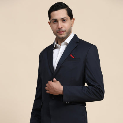 Man wearing a navy suit with a white shirt and red pocket square on a beige background