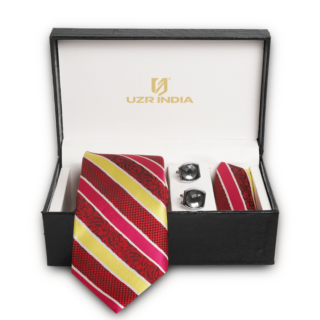 A men's formal accessory gift set in an open black presentation box. The set includes a striped red, pink, and yellow necktie, matching pocket square, and two silver cufflinks.