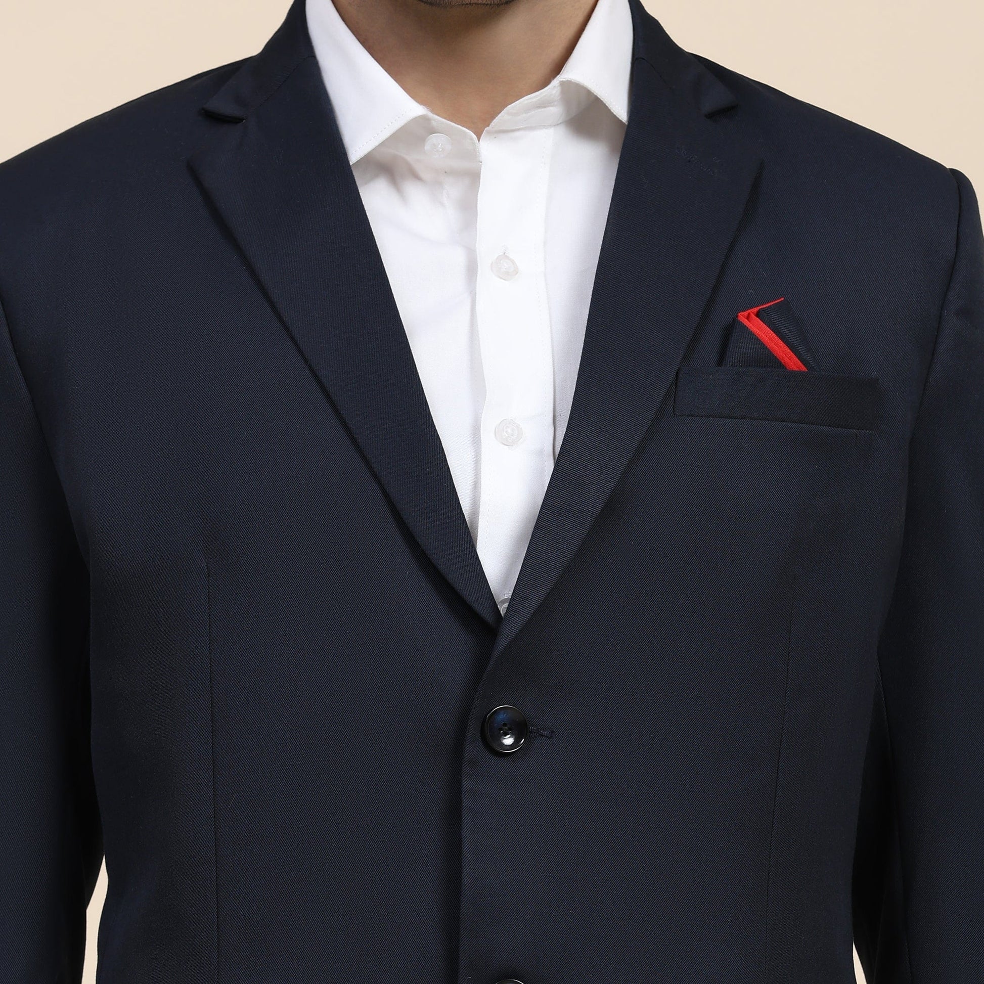 Navy suit jacket with a white shirt and red pocket square on a beige background