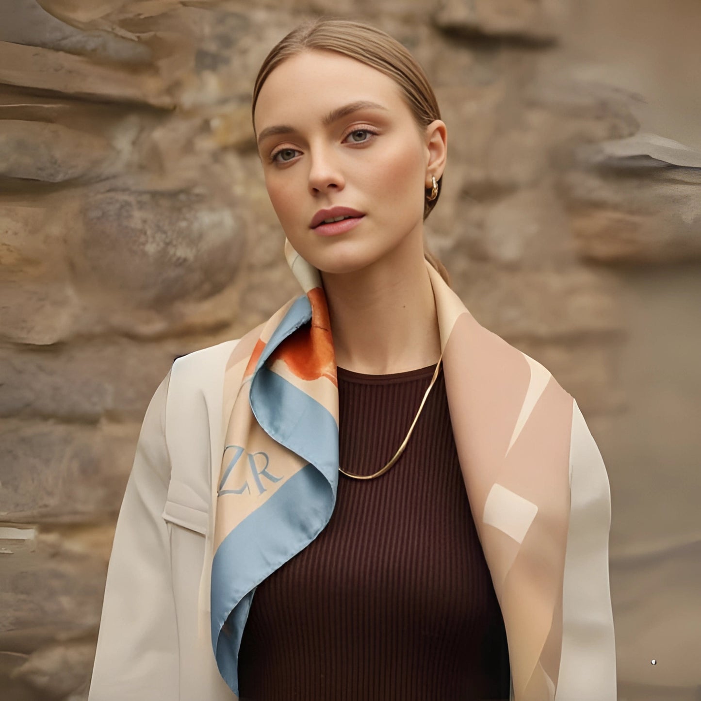 Woman wearing a patterned scarf against a stone wall background